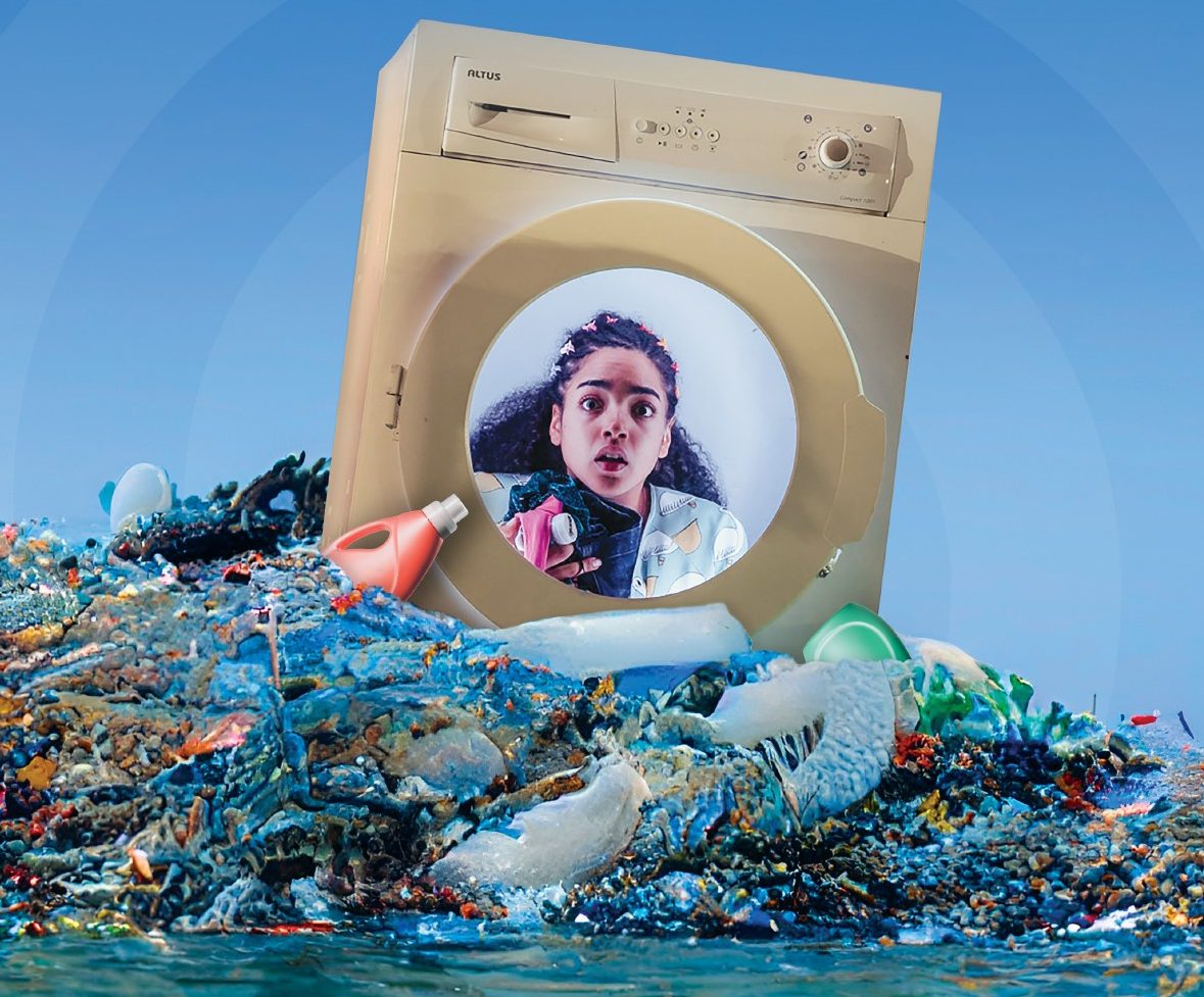 a washing machine sits on top of a pile of plastic waste in the middle of the ocean. Inside the washing machine is a young woman with long hair looking shocked