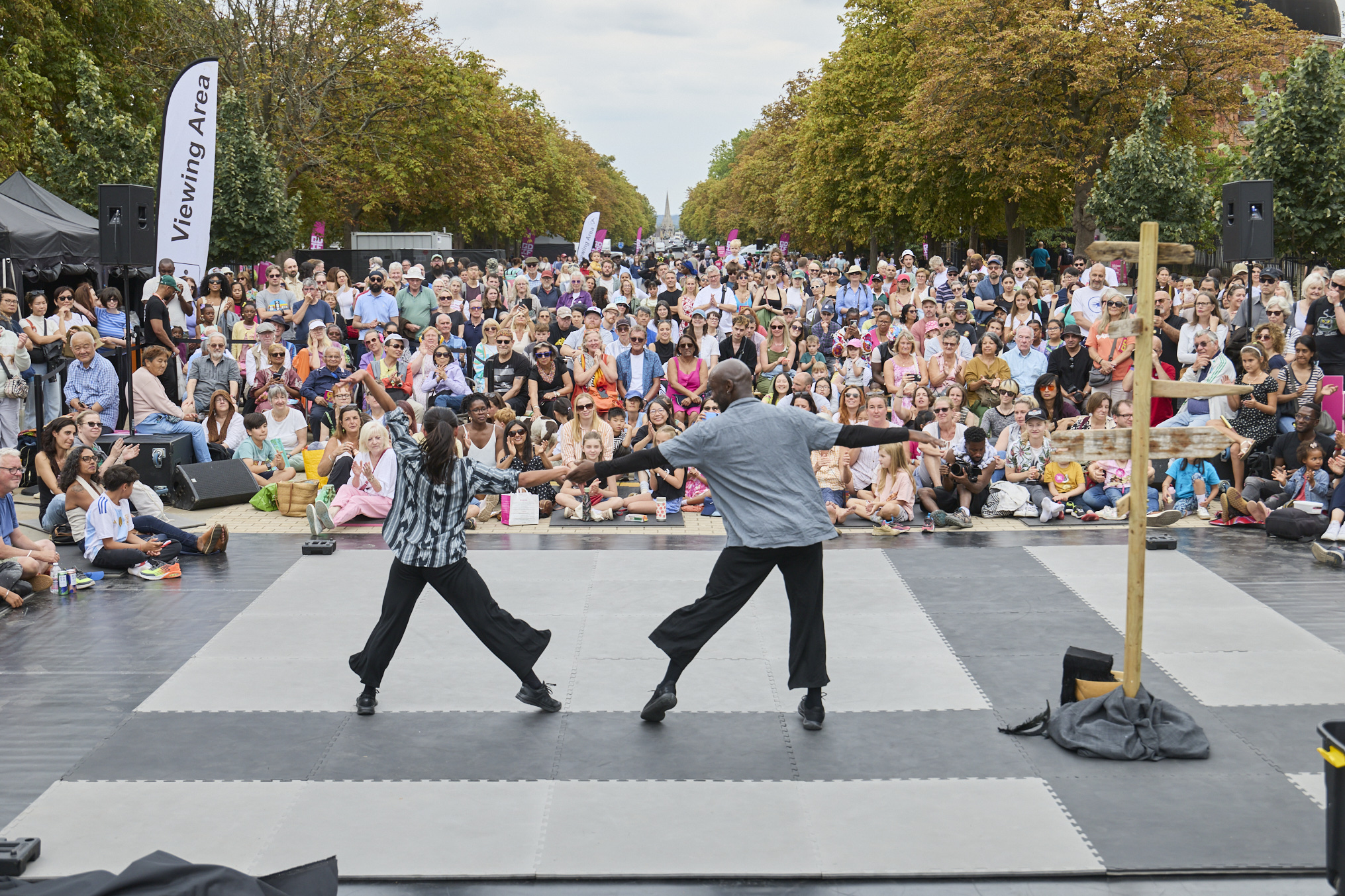 Two dancers with their back to the camera hold hands and as a large crowd looks on in happiness